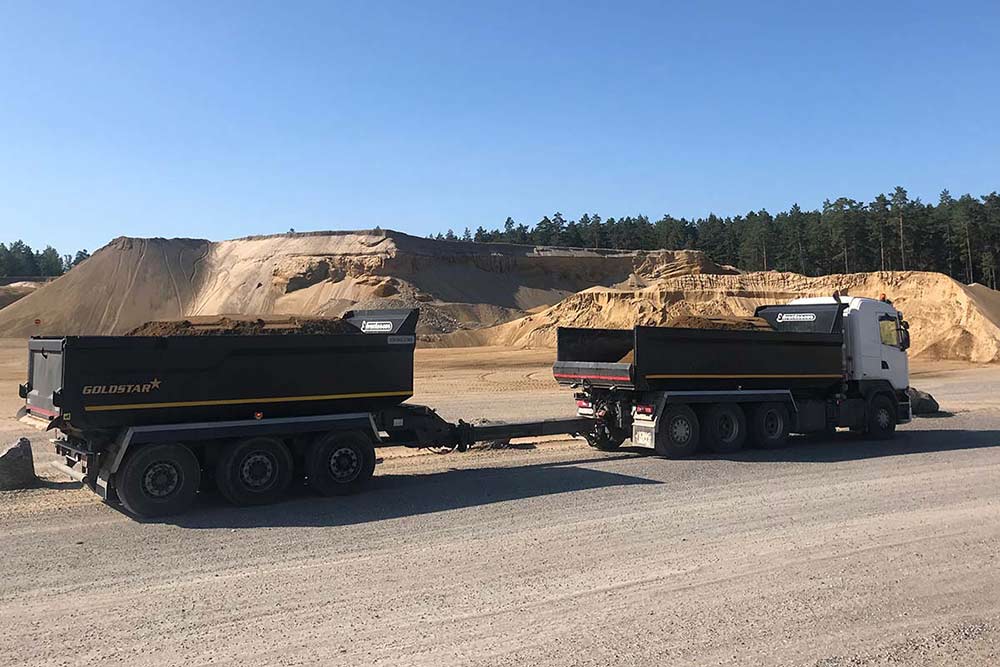 En lastbil med lastsläp fyllda med sand